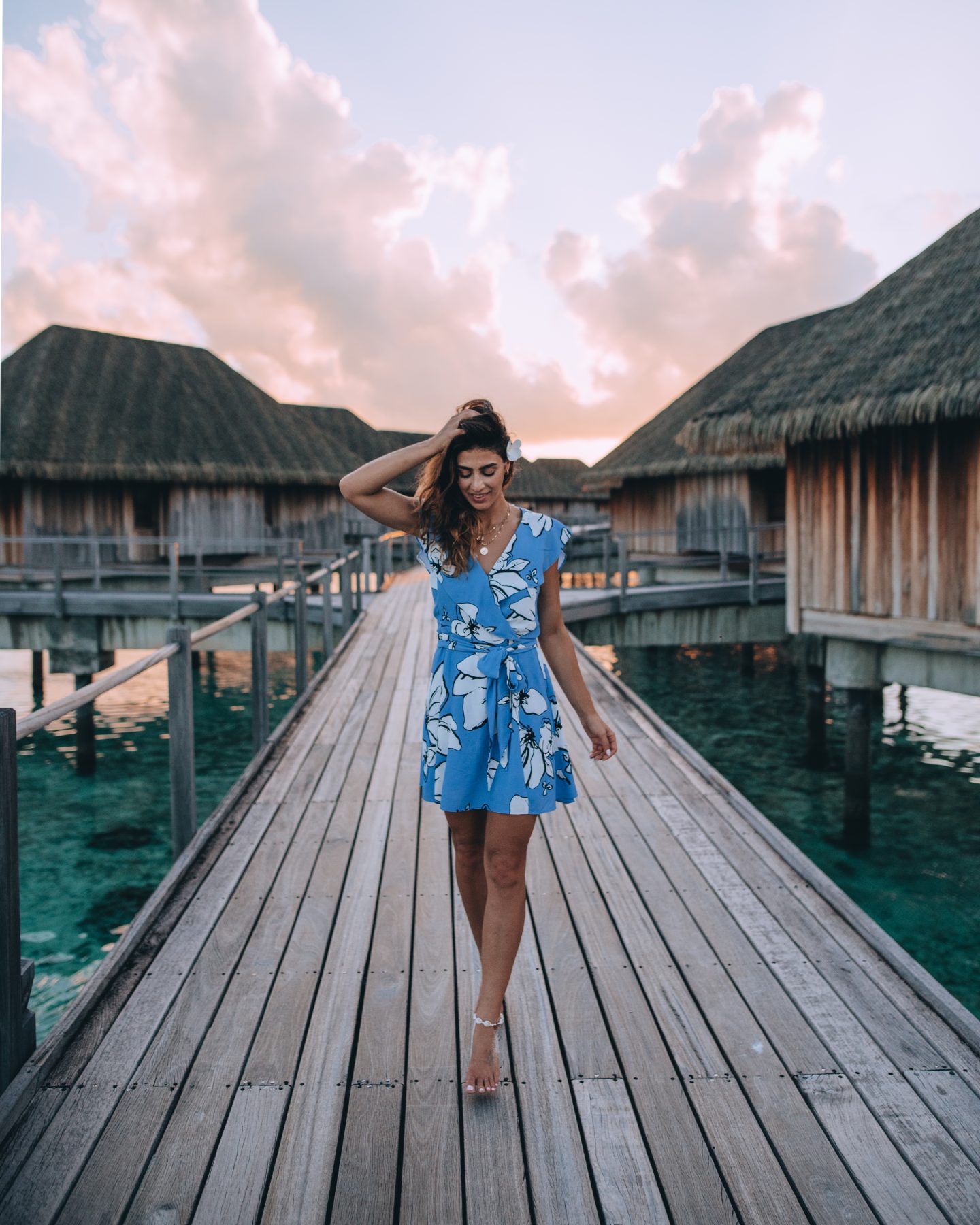 Woman walking down the walkway over the water at Club Med Kani in the Maldives