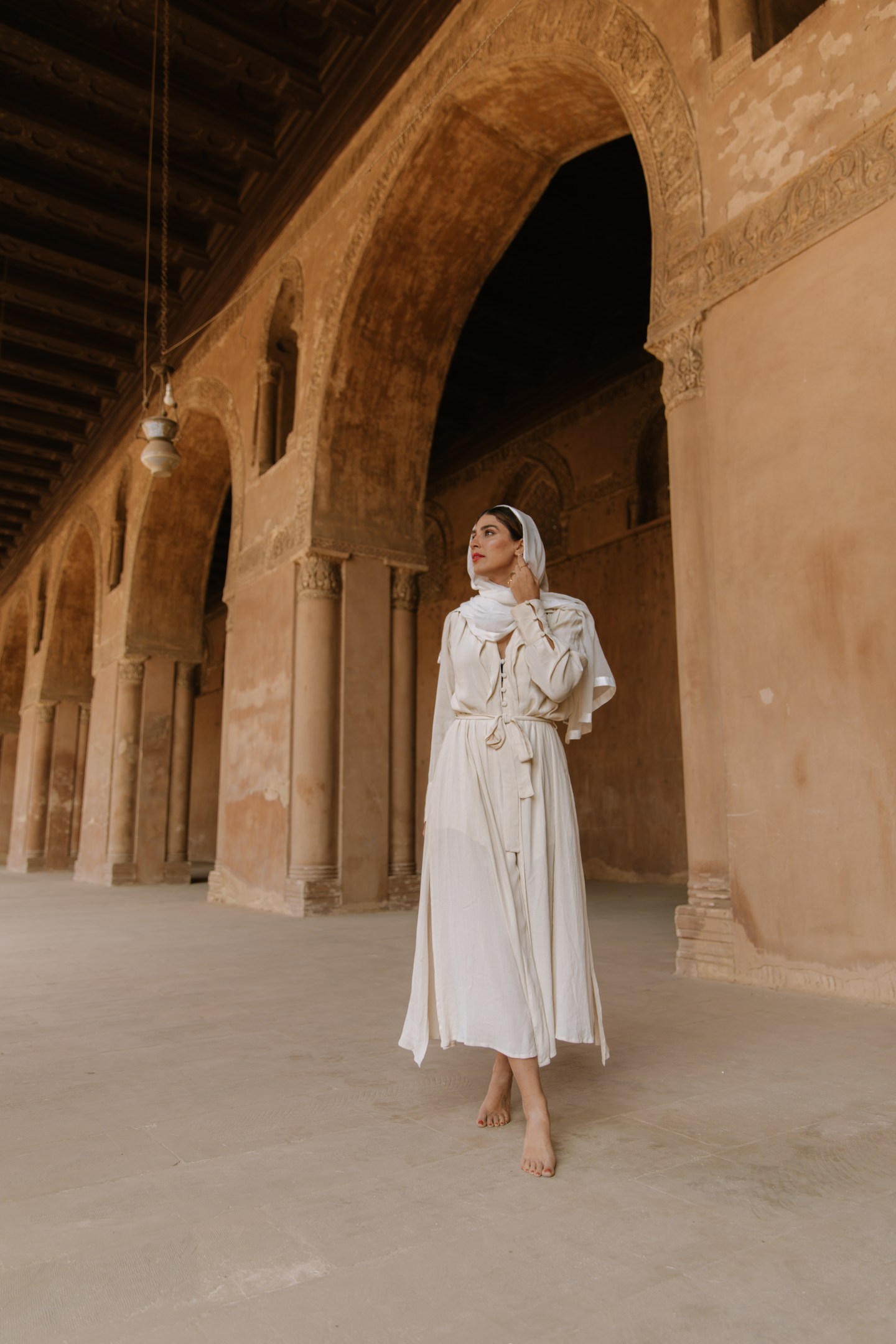 Girl walking through a mosque wearing a cream dress and head scarf