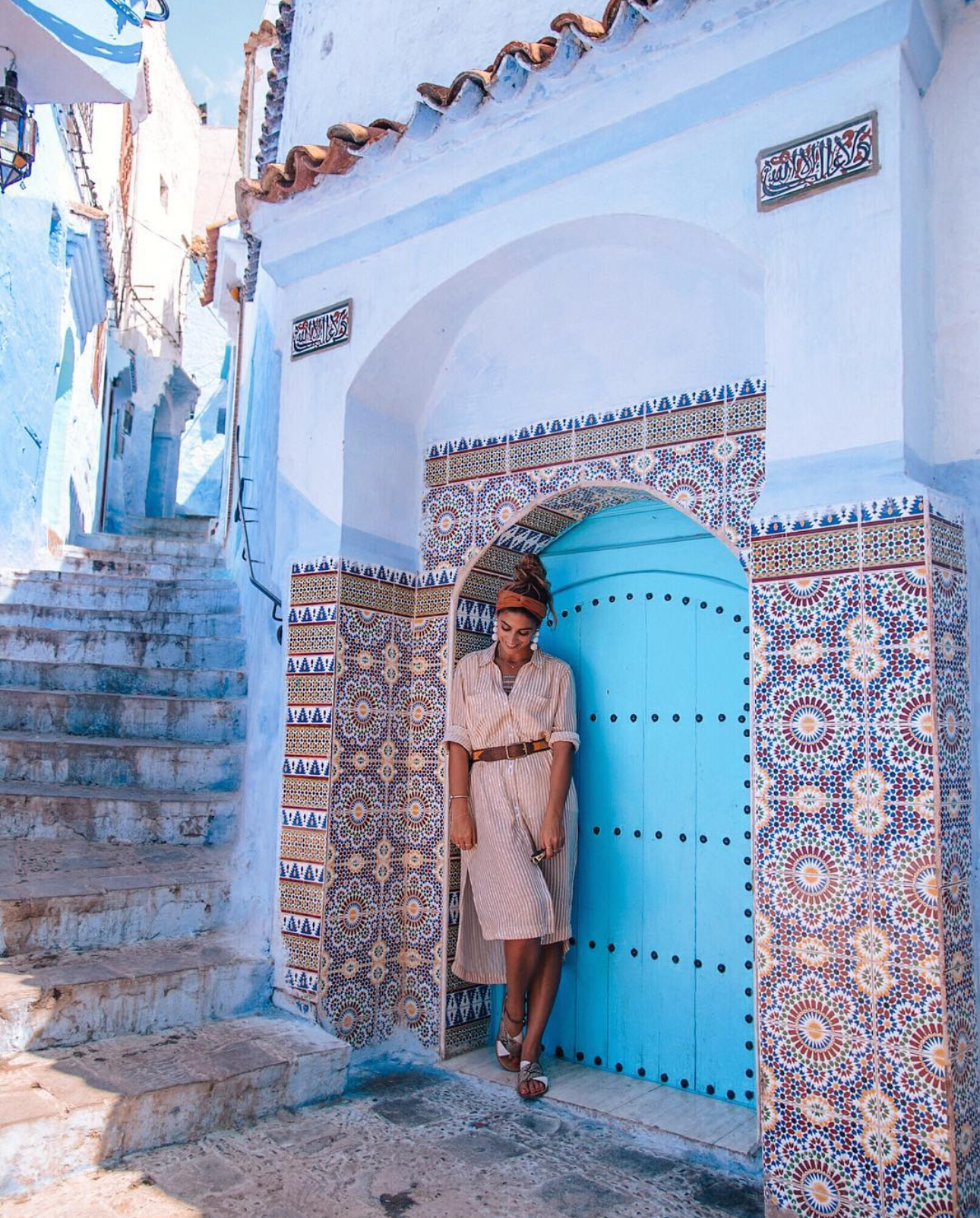 Girl posing at doorway in the blue city Chefchaouen, Morocco