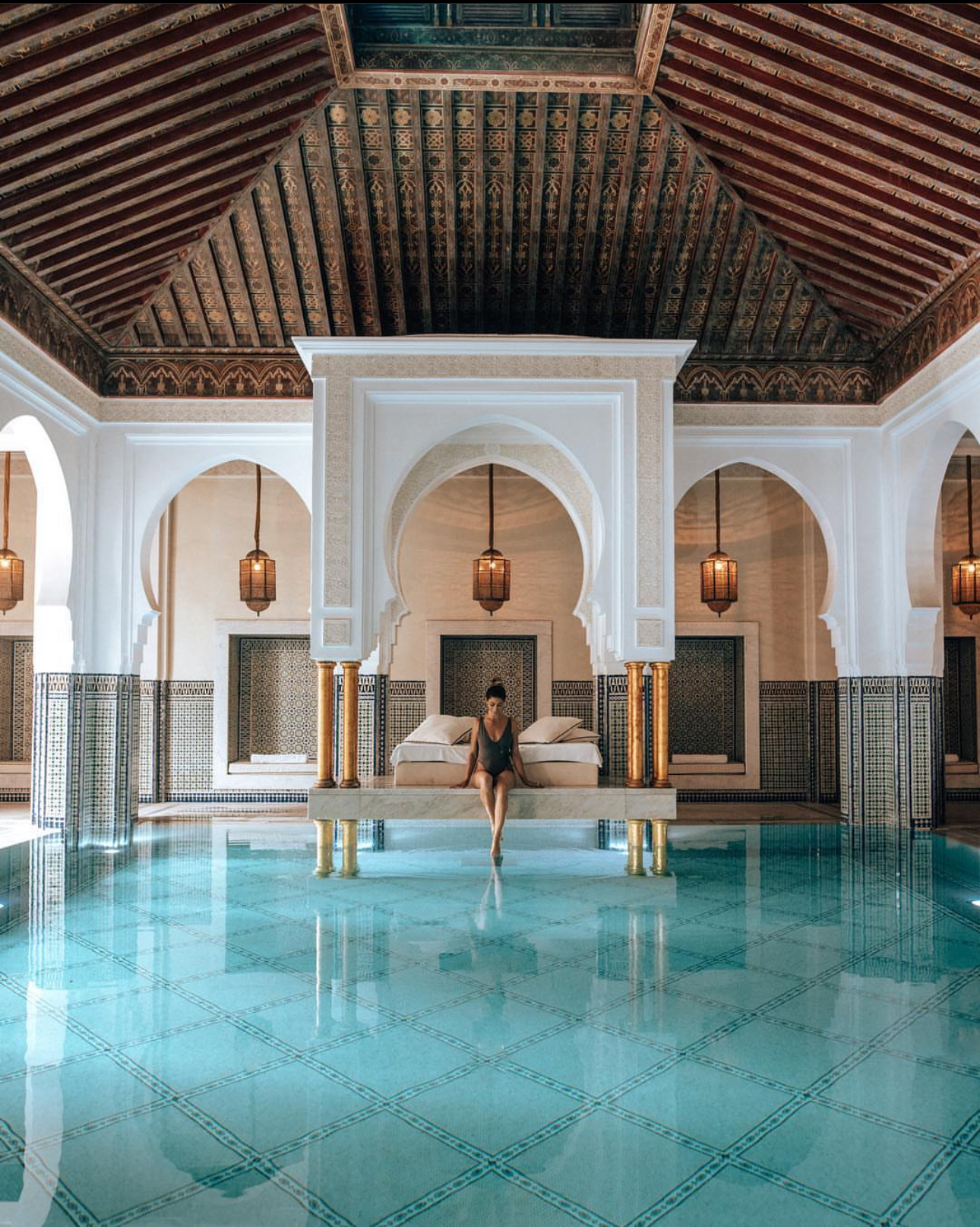 Girl posing on a bed in the famous pool at La Mamounia in Marrakech, Morocco. A perfectly symmetrical photo.