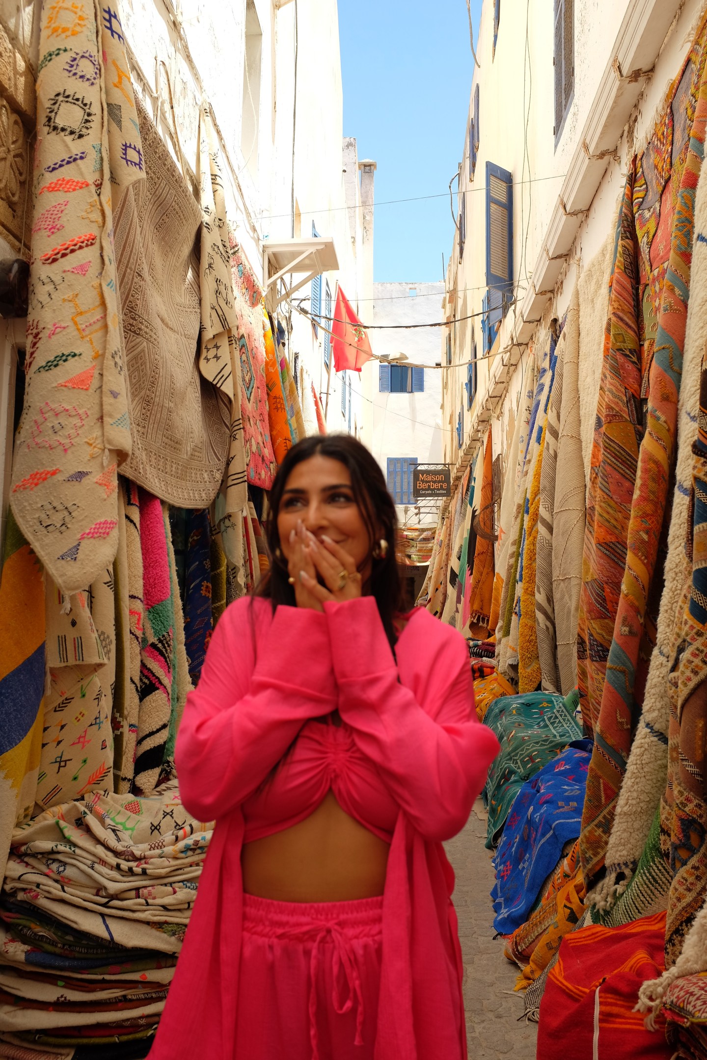 Girl standing in rug heaven in awe of all the colourful rugs that line the streets of Essaouira